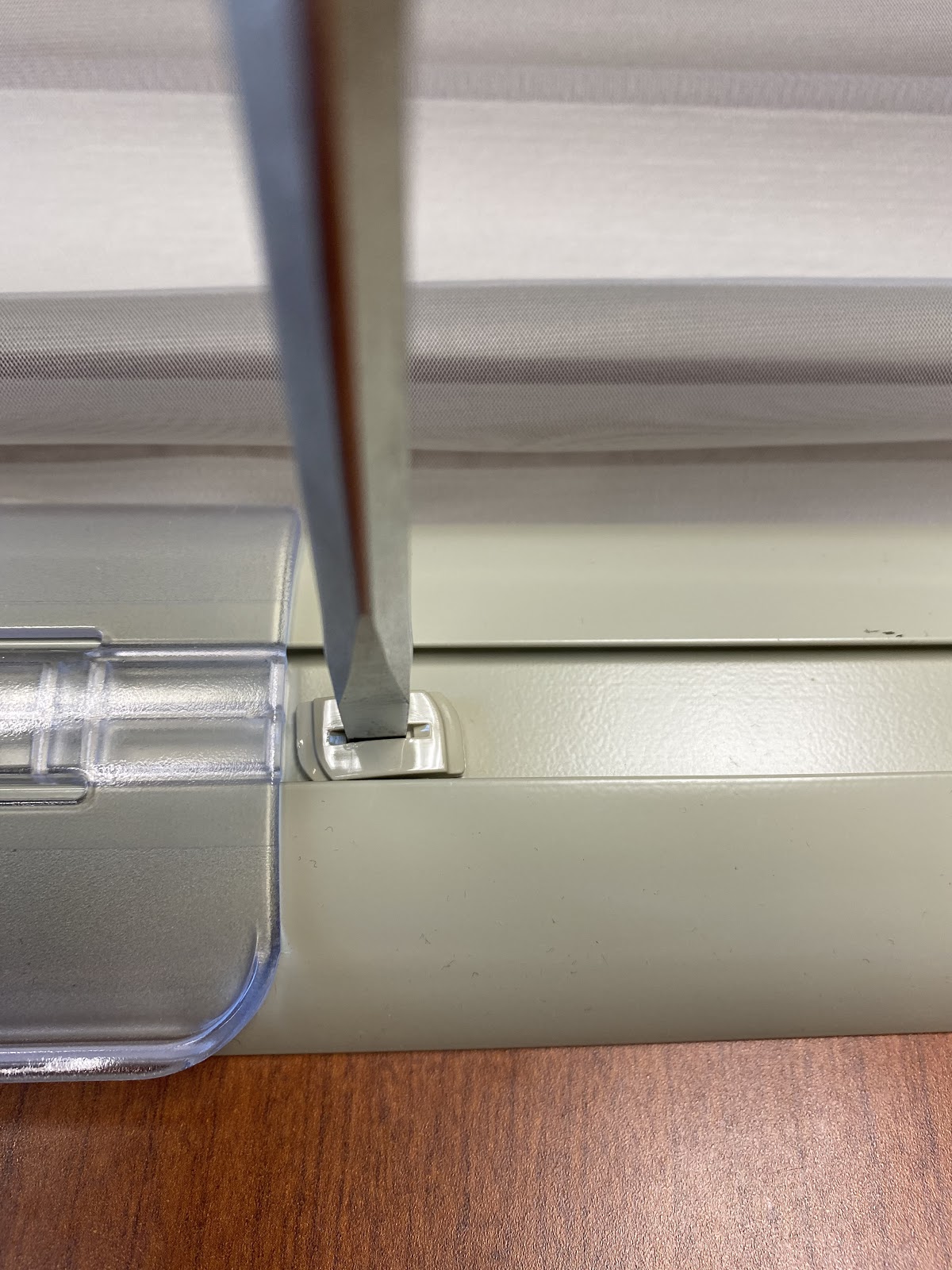 On the same side of the bottom rail that you removed the bottom rail end cap from, use a flathead screwdriver to release the cam lock of the weight clip..jpg